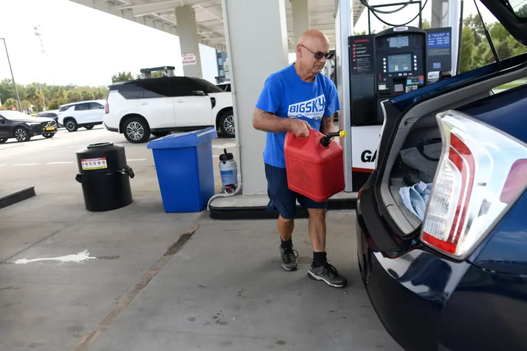 A resident walks to his vehicle after filling up a...