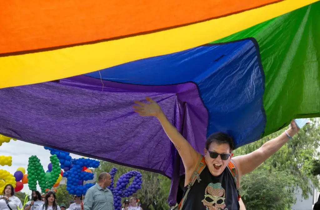 Spencer Mulford helps carry a 33-foot-by-24-foot pride flag during the...