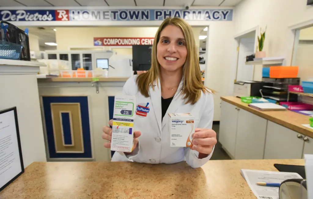 Pharmacist Sarah Ferry holds up A package of GLP-1 medication...