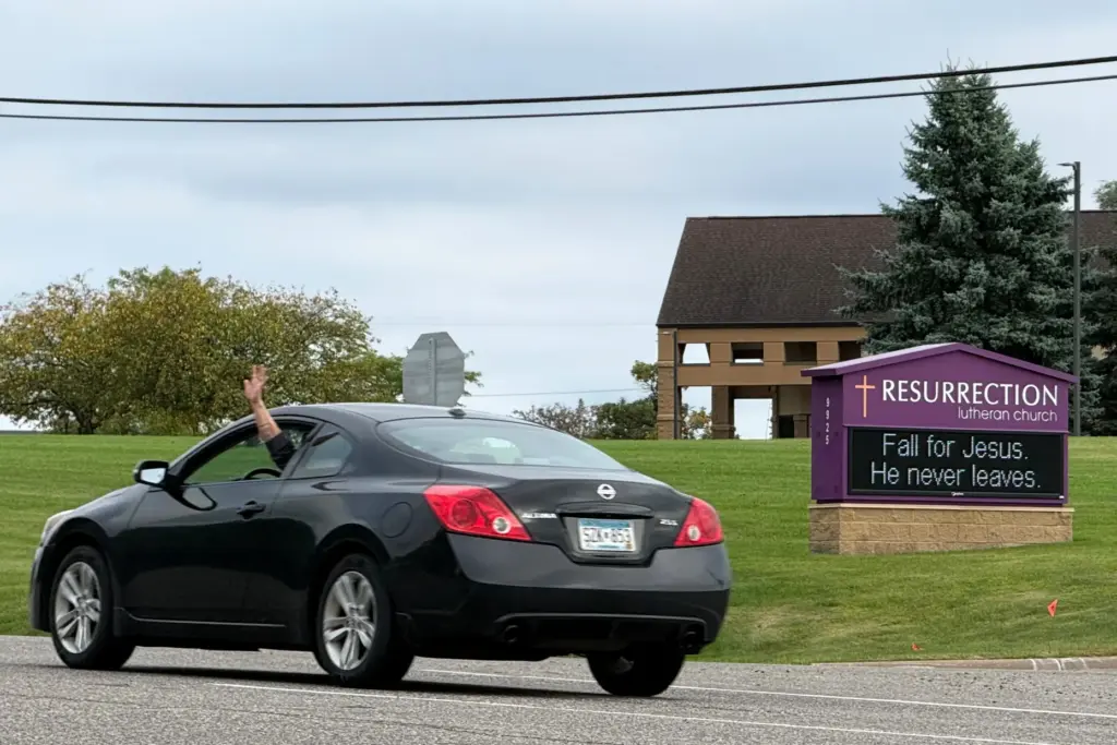 A driver waves while passing in front of Resurrection Lutheran...