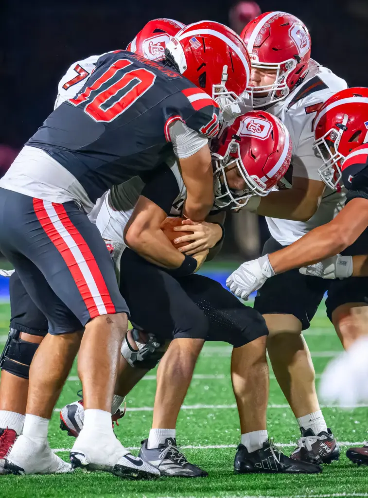 Orange Lutheran quarterback Reagan Toki, center, is sacked by Mater...