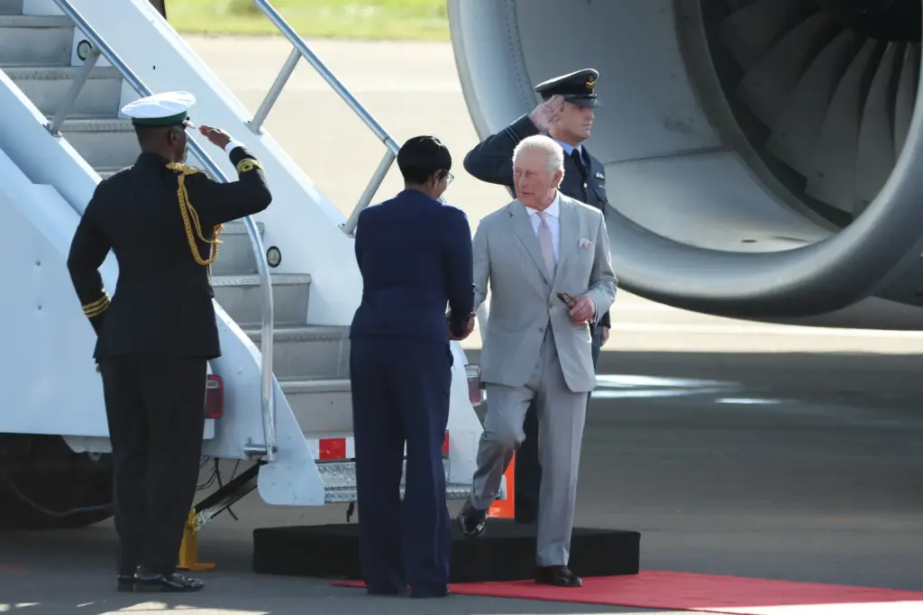 Britain’s King Charles III is welcomed as he deplanes at...