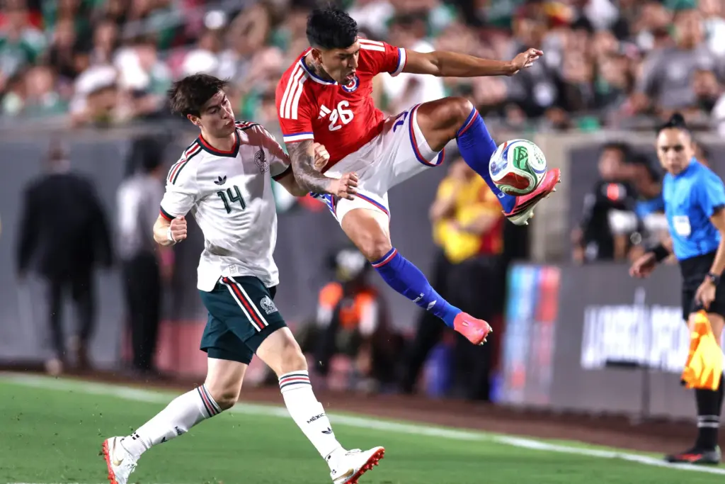 Chile defender Diego Ulloa, right, kicks the ball while being...